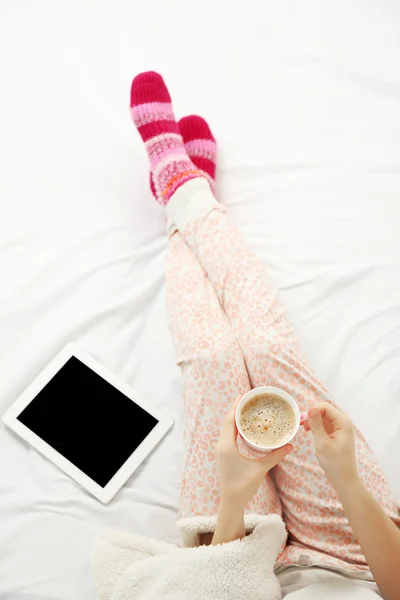 Woman in pajamas with tablet drinking coffee — Stock Photo, Image