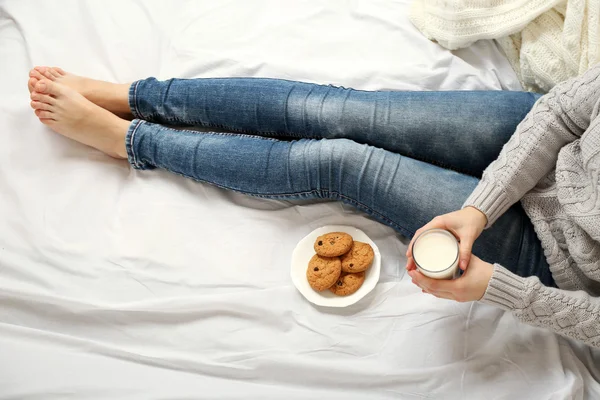 Frau trinkt Milch mit Keksen auf ihrem Bett — Stockfoto