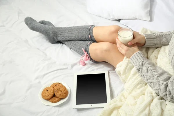 Frau mit Tablette trinkt Milch auf ihrem Bett — Stockfoto