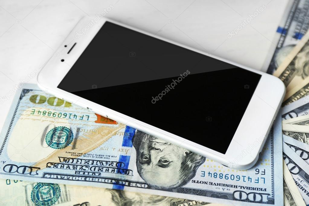 Smart phone with dollar banknotes on light table. Internet earning concept