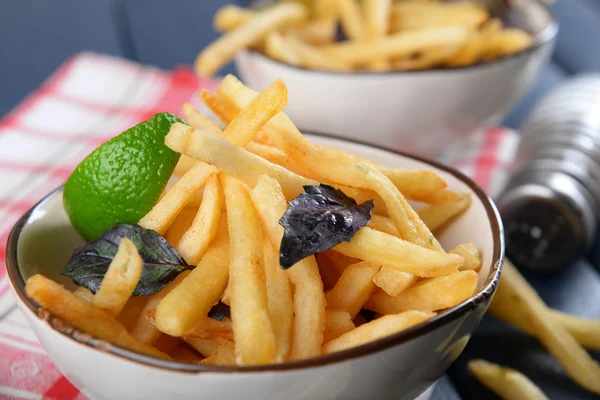 Pommes frittierte Kartoffeln in Schüssel mit Basilikum und Soße auf altem Holzgrund — Stockfoto