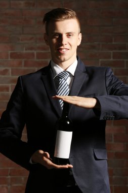 Bir şişe kırmızı şarap tutan adam