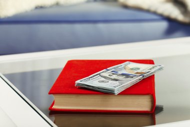 Cam masa Doları banknot yığını ile kırmızı kitap