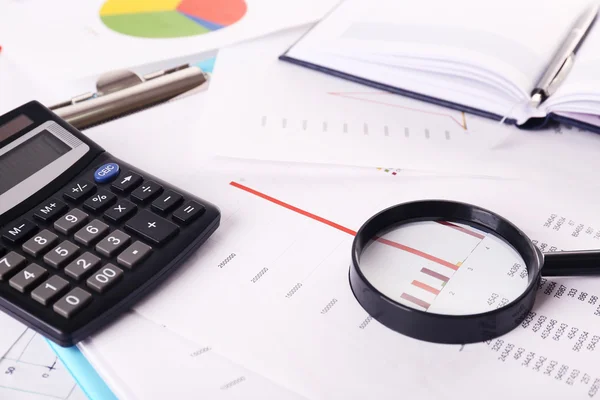 A magnifying glass on financial documents — Stock Photo, Image