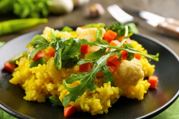 Assiette noire avec risotto aux légumes sur table en bois servie — Photo