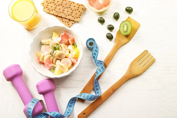 水果沙拉和木制背景上的哑铃。健康饮食概念. — 图库照片