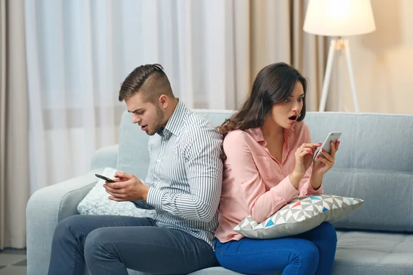 Casal com telefones celulares em casa — Fotografia de Stock