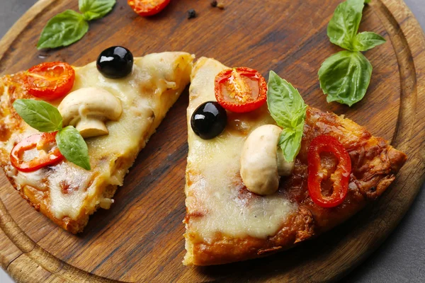 Fette di pizza saporita su asse di legno rotonda, primo piano — Foto Stock