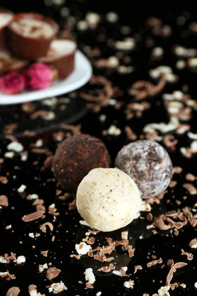 Bonbons au chocolat assortis avec des flocons sur fond noir — Photo