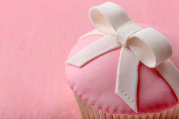 Tasty cupcake with bow on color wooden background — Stock Photo, Image