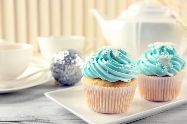 Dos sabrosos cupcakes azules con decoraciones sobre fondo claro — Foto de Stock