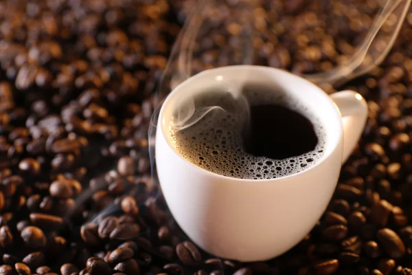 Kopje hete koffie op koffie bonen achtergrond — Stockfoto