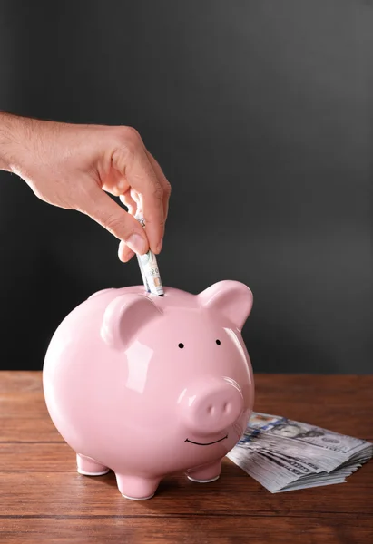 Man putting money in moneybox — Stock Photo, Image