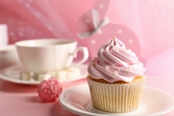 Tasty cupcake with tea set and decorations on pink background — Stock Photo, Image