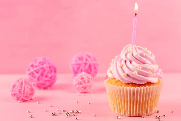 Tasty cupcake with candle and decorations on pink background — Stock Photo, Image