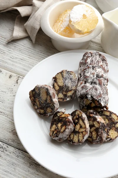 Salami de chocolate en un plato sobre fondo de madera — Foto de Stock