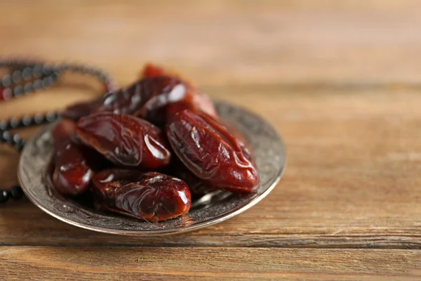 Dates fruit and rosary on wooden background, close up — Stock Photo, Image