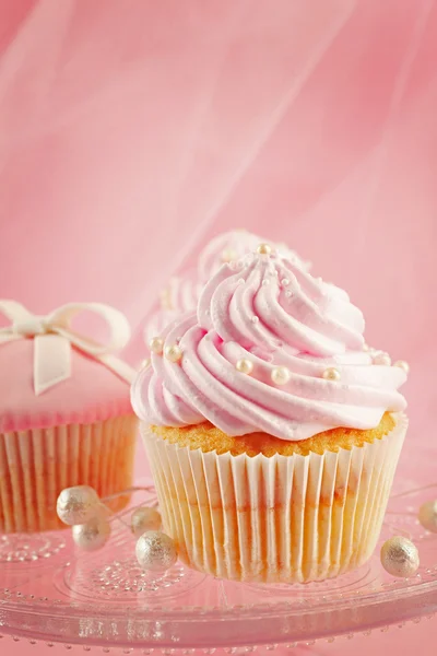 Några läckra cupcakes med dekorationer på rosa bakgrund — Stockfoto