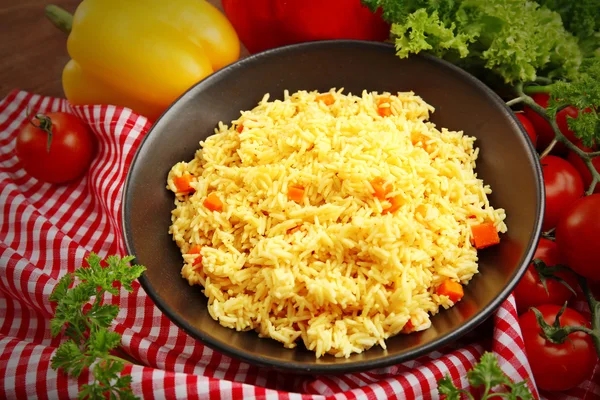 Stewed rice with a carrot on a black plate — Stock Photo, Image