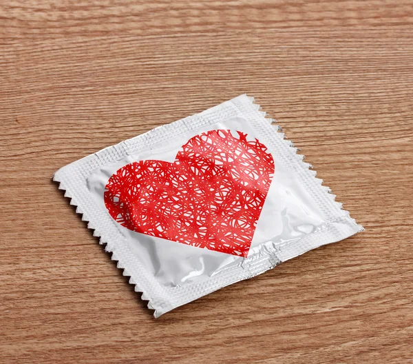 Condom with heart on table — Stock Photo, Image