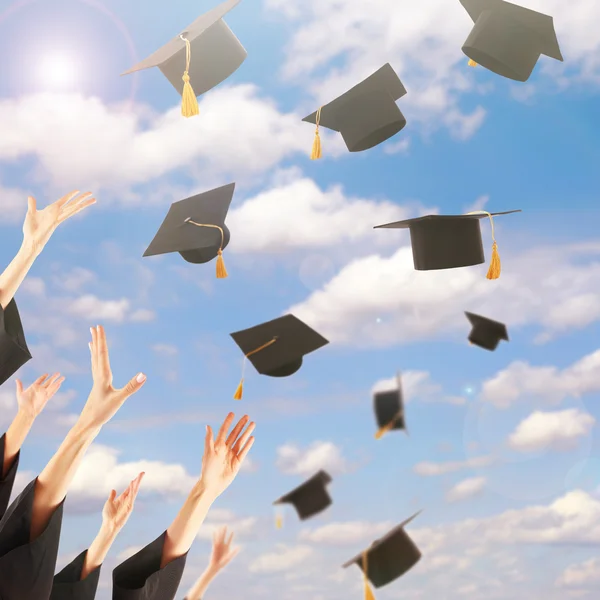 Estudiantes lanzando sombreros de graduación — Foto de Stock