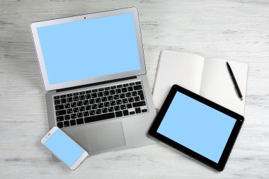 Modern dizüstü bilgisayar, cep telefonu, tablet ve defter Beyaz ahşap zemin üzerinde