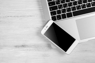 Modern dizüstü bilgisayar ve cep telefonu Beyaz ahşap zemin üzerinde