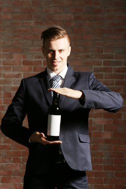 Bir şişe kırmızı şarap tutan adam