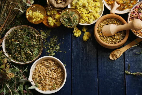 Surtido de hierbas medicinales secas en cuencos sobre fondo de madera vista superior —  Fotos de Stock