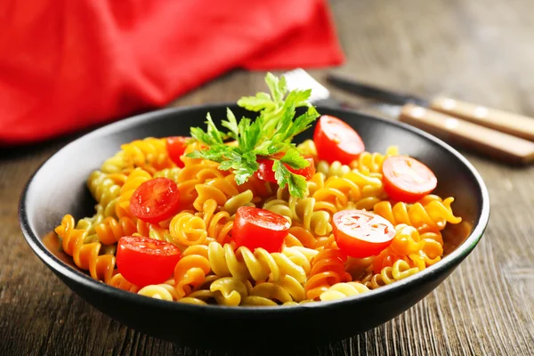 Delicioso plato de macarrones en tazón negro sobre mesa de madera servida — Foto de Stock