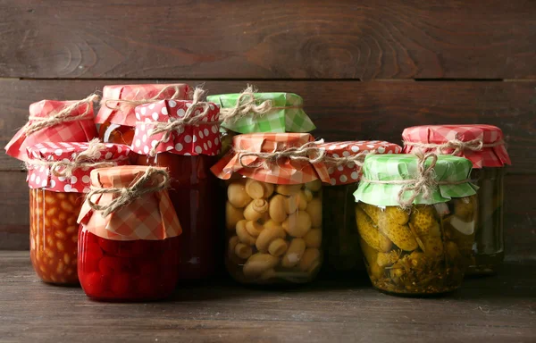 Frascos con verduras y frijoles en vinagre sobre fondo de madera —  Fotos de Stock