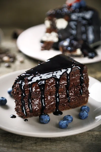 Κέικ σοκολάτας με σοκολάτα κρέμα και τα φρέσκα βακκίνια στο πιάτο, σε ξύλινο φόντο — Φωτογραφία Αρχείου