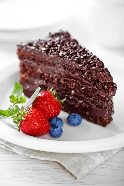 Kue coklat dengan krim coklat dan buah beri segar di piring, dengan latar belakang cahaya — Stok Foto