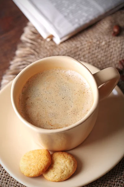 Cup of coffee, cookie and newspaper on wooden table background — Stock Photo, Image