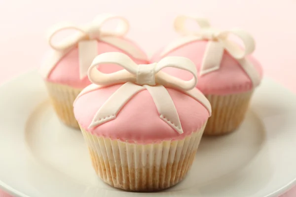 Tasty cupcakes with bow on color wooden background — Stock Photo, Image