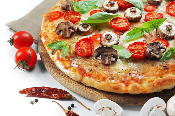 Pizza saborosa e legumes frescos na tábua de madeira redonda, close-up — Fotografia de Stock