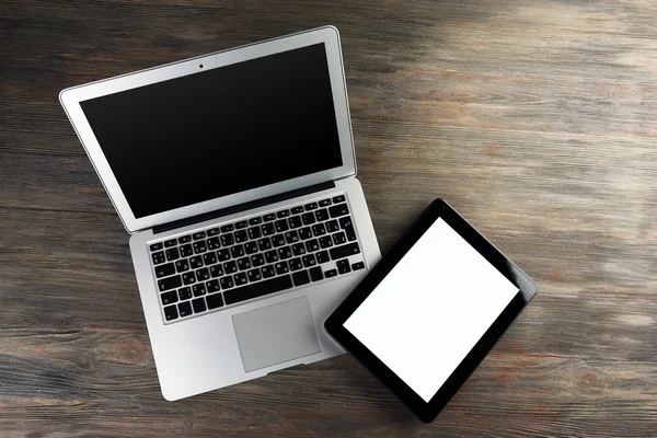 An open silver laptop and modern tablet on the wooden background — Stock Photo, Image