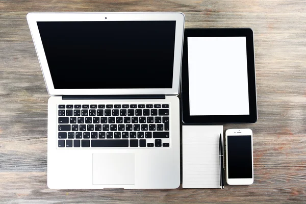 Laptop moderno, tablet, telefone celular e notebook na mesa — Fotografia de Stock