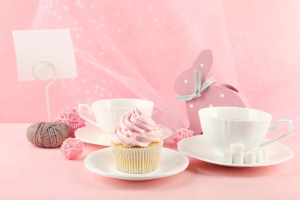 Gâteau savoureux avec ensemble de thé et décorations sur fond rose — Photo