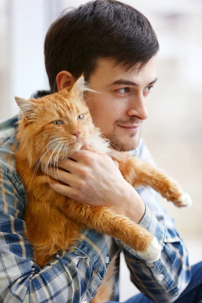 Молодой человек с пушистым красным котом — стоковое фото