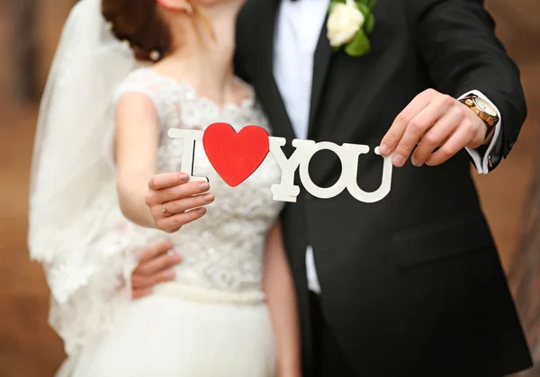 Casal segurando inscrição com coração — Fotografia de Stock