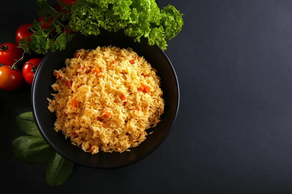 Stuvade ris med en morot och tomater på ett fat över svart bakgrund — Stockfoto