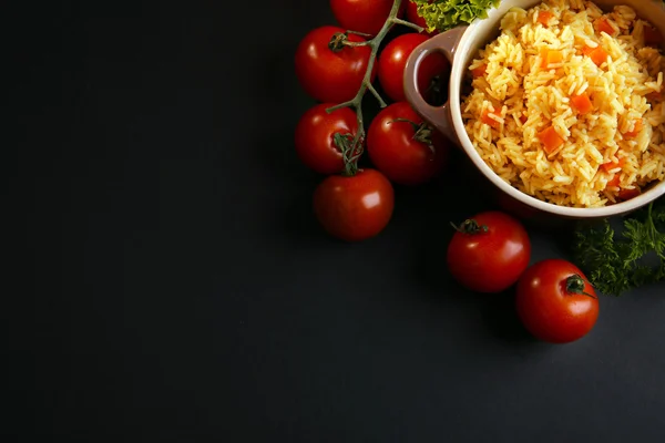 Stuvade ris med en morot och tomater i ett kokkärl över svart bakgrund — Stockfoto