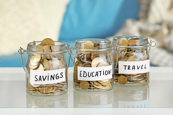 Glass jars with Ukrainian coins for savings, education and travel on a table — Stock Photo, Image