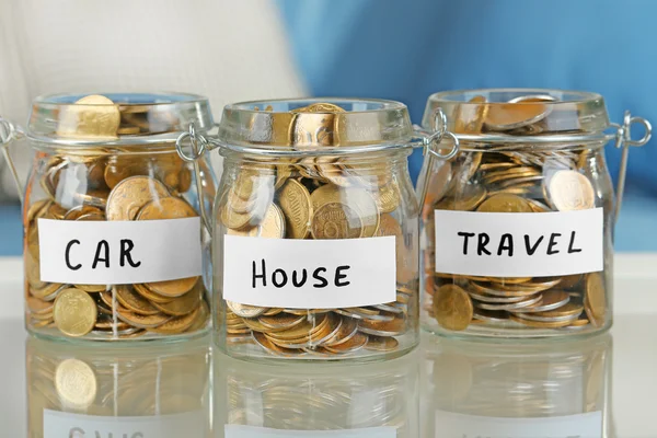 Glass jars with Ukrainian coins for car, house and travel on a table — Stock Photo, Image