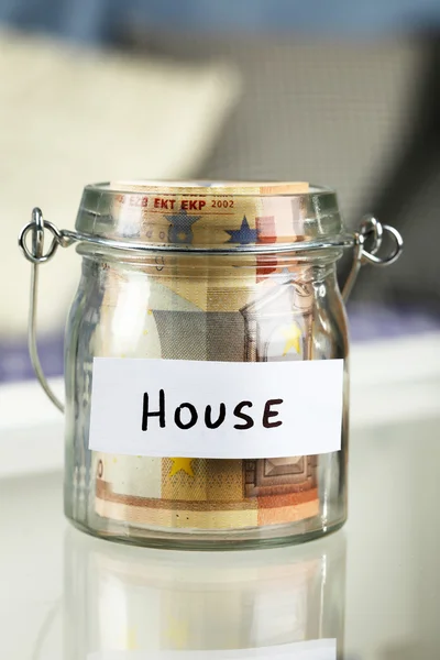 Glass jar with euro banknotes for house on a table — Stock Photo, Image