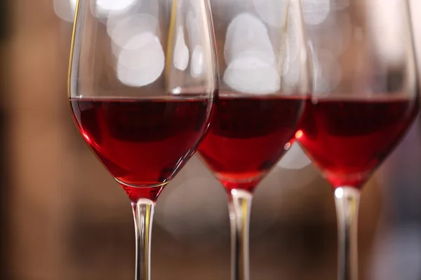 Bril met rode wijn op onscherpe achtergrond — Stockfoto