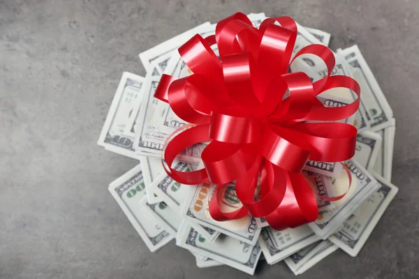 Pile of dollars with bow as gift — Stock Photo, Image