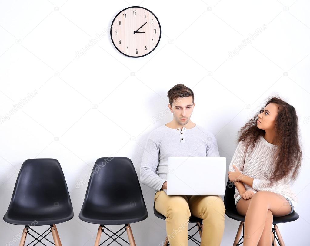 Young boy using laptop and woman looking at the clock in white hall