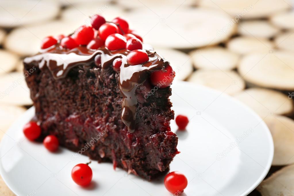 Piece of chocolate cake with cranberries on wooden background, closeup